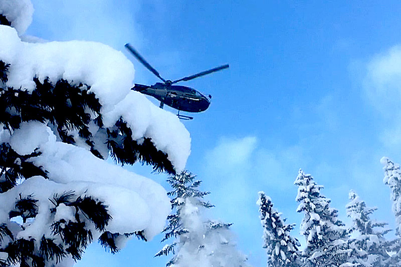 Hubschrauber über tief verschneiten Bäumen